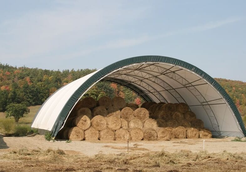A large open-ended storage shelter filled with hay bales.